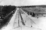 KL Dachau - Gesamtblick auf die Baracken, wo die Gefangenen lebten, Stacheldrahtzaun, durch den elektrischer Strom unter hohen Spannung floss, neben der Baracken stehen Gefangene; April 1945 (AIPN)